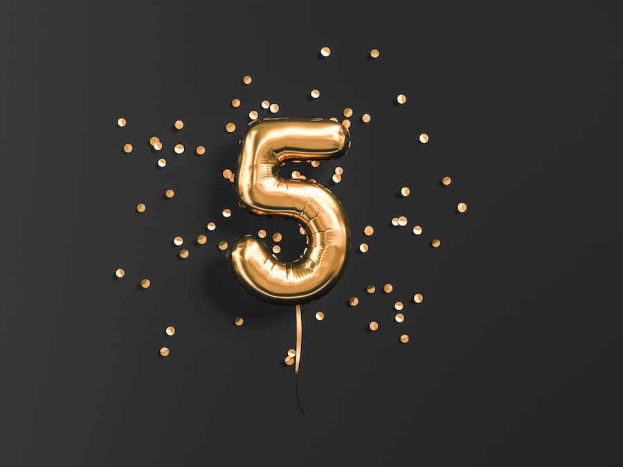 Five year birthday. Number 5 flying foil balloon and gold confetti on black. Five-year anniversary background. 3d rendering